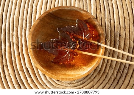 A top down view of some maple leaf hard candy lollipops.