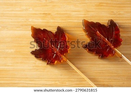 A top down view of some maple leaf hard candy lollipops.