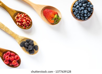 Top down view of spoons filled with berries and a bowl with blueberries. healthy antioxidant concept. - Powered by Shutterstock