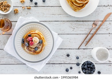 Top Down View Of A Stack Of Buttermilk Pancakes Topped With Fruit And Syrup Ready For Eating.