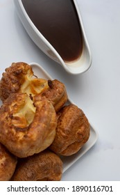 A Top Down View Of A Stack Of Yorkshire Puddings On A White Backdrop With A Filled Gravy Boat