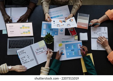 Top Down View At Table With Documents And Diverse Team Discussing Marketing Data