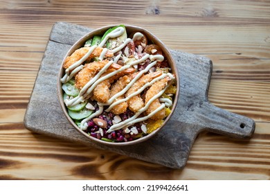 Top down view of tasty torpedo shrimp salad take-away bowl on wooden cutting board