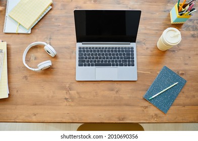 Top Down View At Teenagers Desk With Opened Laptop On Wooden Table And Accessories, Copy Space