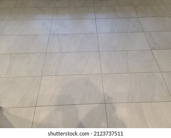 A Top Down View Of A Tile Floor. The New Tile Flooring Is A Neutral, Gradient, White Color.