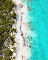 Top Down View Of Untouched An Undeveloped Coast In The Turks And Caicos Islands With Natural Rocky Coastline Balanced By Green Tropical Plants On Left And Turquoise Caribbean Sea On The Right