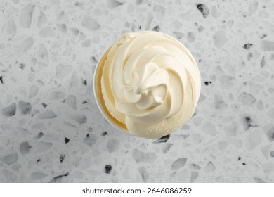 A top down view of vanilla soft serve ice cream in a cup.