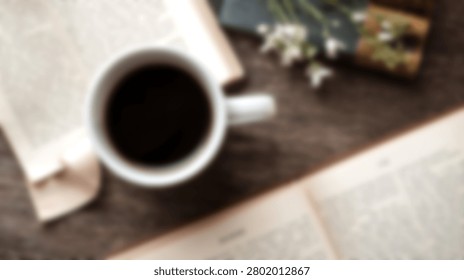 A top down view of a white mug filled with black coffee placed beside open book pages on a dark wood surface
