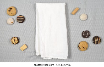 Top Down View Of White Tea Towel Surrounded By Delicious Cookies.