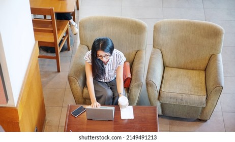 Top Down View Of Young Woman Using Laptop And Smartphone On The Table While Sitting In The Cafe