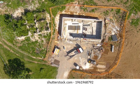 TOP DOWN: Workers prepare walls for concrete pouring at a house under construction in the sunny countryside. Flying above modern construction site as groups of contractors works on preparing the walls
