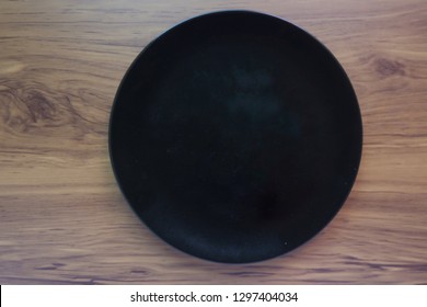 Top Eye View Full Of Single Circle Empty Black Plate On A Wooden Striped Table Background At The Kitchen Counter And Space For Text