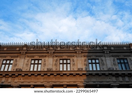 Top floor of historical building in neoclassical architecture style with row of architrave windows with molded lions, balustrade and dentil decorations