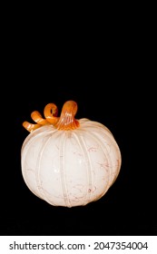 Top, Front View, Medium Distance Of An Artisan White, Blown Glass Pumpkin, With Orange Trim On Black Background 