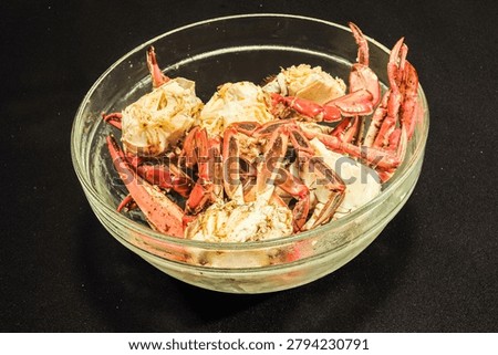 top, front view, medium distance of, a glass bowl of, half split, steamed, blue claw crabs, with black background, under studio strobe lighting