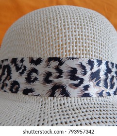 Top half of ladies white plastic mesh sunhat with hatband in cream and brown and black.