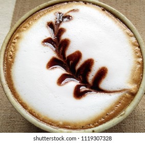 Top of a hot cappuccino with the leaf pattern decoration on milk foam