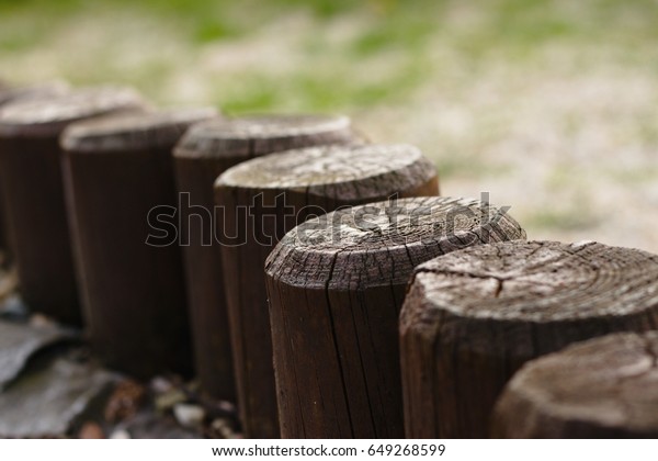 Top of low wooden\
palisade forming a fence