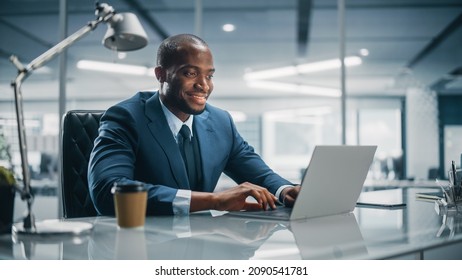 Top Management Modern Office: Successful Black Businessman in Tailored Suit Working on Laptop Computer. Professional African American CEO Managing Investment Strategy. Portrait of Top Manager