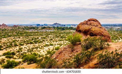 Top of one of the red sandstone buttes of Papago Park, with its many caves and crevasses caused by erosion under cloudy sky, in the city of Tempe, Arizona in the United States of America
