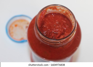 The Top Of An Open Jar Of Tomato Pasta Sauce. Tomato Puree Sauce In A Jar With The Lid In The Background