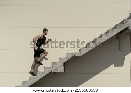 Up to top, overcoming challenges. Strong athletic man climbing stairs