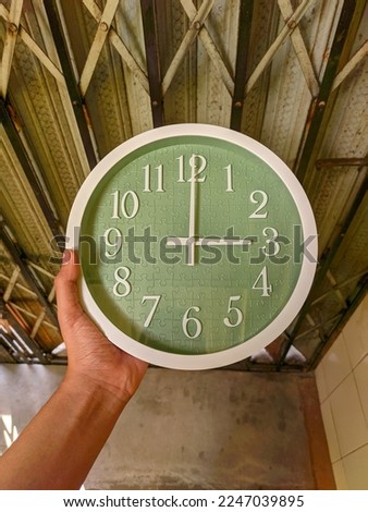 top photo of modern wall clock reflecting light held by hand with indoor light.  selective focus