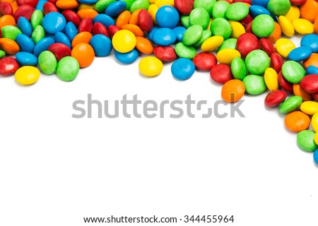 Top right frame of colorful chocolate coated candy on white background with space for text