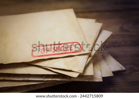 Top Secret stamp. Stacked old letters on wooden table, closeup