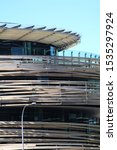Top section of the modern Darling Square Library with blue sky in the background. Knick named "the birds nest". Spiral-like building wrapped in timber ribbons. Sydney