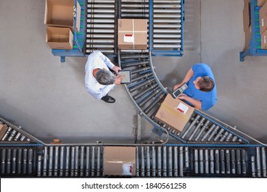 Top shot of a worker speaking to a supervisor with a digital tablet while scanning boxes on a conveyor belt at a distribution warehouse. - Powered by Shutterstock