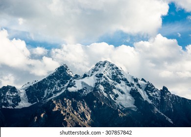 Top Of Snowy Rock Mountain On Cloudy Background