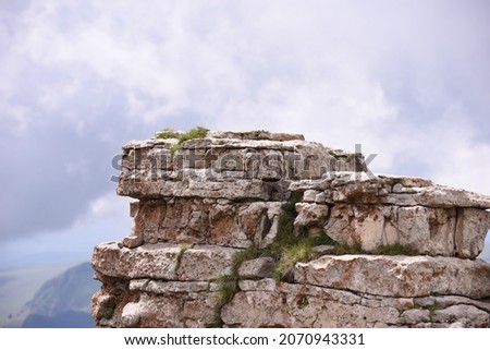 the top of a stone cliff, a rocky ledge against a background of clouds, folded by a layered layer of limestone, look at one level