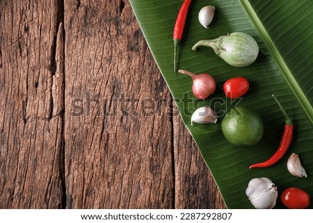 Top Table View of Vegetables and herbs, fresh, placed on banana leaves, on old wooden table