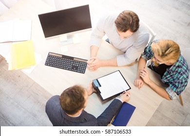 Top toned of bank officer offering agreement or contract to young couple for getting credit card for buying apartment or flat. Bank and money concepts.