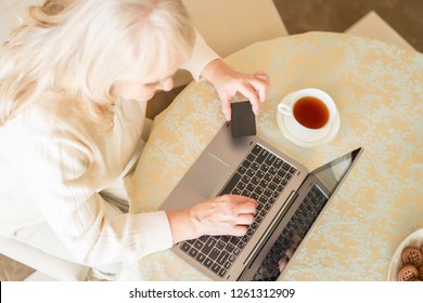 Top Vies On Elderly Woman Making Paying Transactions With The Help Of A Credit Card Over A Cup Of Tea.