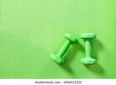 Top View, 2 Green Dumbbells Flat Lay On Yoga Mat, Set Of Indoor Exercise Equipment. Lifestyle Workout At Home. Monochromatic Color Objects On Pattern Texture With Copy Space. Wellness, Healthy Concept