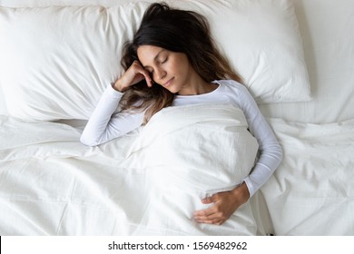 Top View 30s Woman Wearing Soft Comfortable Night Clothes Lying Down On The Fresh White Color Sheets Having Nap In Bed Sleeping In Bedroom At Home Alone. Refreshment, Renew Energy And Strength Concept