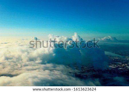 Top view above the clouds and the city, smoke from the pipes of plants and clouds.