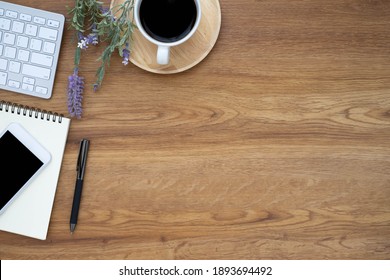 Top view above of Wooden office desk table with keyboard, coffee cup and notebook, phone with equipment office supplies. Business and finance concept. Workplace, Flat lay with blank copy space.