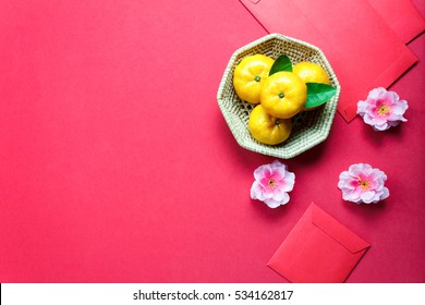 Top view accessories Chinese new year festival decorations.orange,leaf,wood basket,red packet,plum blossom on red background.