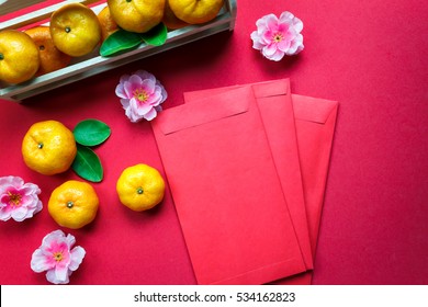 Top view accessories Chinese new year festival decorations.orange,leaf,wood basket,red packet,plum blossom on red background.