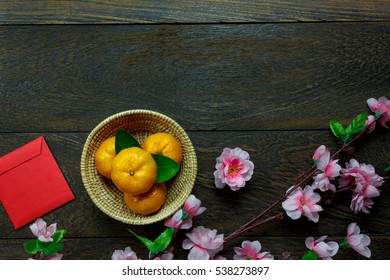 Top view accessories Chinese new year festival decorations.orange,leaf,wood basket,red packet,plum blossom on table wooden background with copy space.