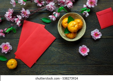 Top View Accessories Chinese New Year Festival Decorations.orange,leaf,wood Basket,red Packet,plum Blossom On Table Wooden Background With Copy Space.