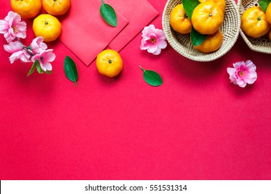 Top view accessories Chinese new year festival decorations.orange,leaf,wood basket,red packet,plum blossom on red background.