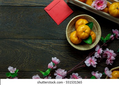 Top View Accessories Chinese New Year Festival Decorations.orange,leaf,wood Basket,red Packet,plum Blossom On Table Wooden Background With Copy Space.