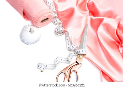 Top view accessories for sewing lie on a white background. Pink satin fabric roll, measuring tape, scissors, needles for sewing. Fashion, Design Studio on tailoring, atelier concept. Desk accessories - Shutterstock ID 520266121
