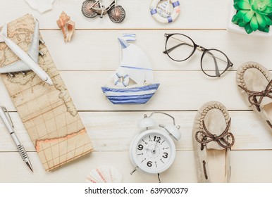 Top View Accessories To Travel Beach.The Woman Shoes Notebook Map Passport Airplane Boat Music Eyeglasses On White  Wooden Background.