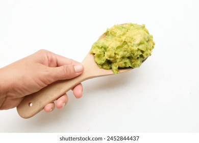 Top view of aDelicious mashed ripe green avocado,Avocado cream ,Mashed avocado sauce,guacamole  served in 
in a wooden spoon in human hands appetizer for vegan dieting isolated on white backdrop - Powered by Shutterstock