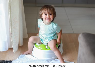 Top view of adorable smiling boy sitting on chamber pot,potty training hygiene. Mixed race Asian-German child learning sit on toilet wc seat at home. Kid about two years old.